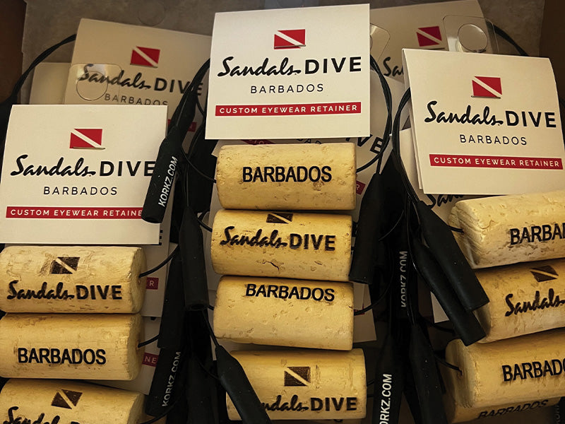 KORKZ custom laser engraved sunglass retainers bulk order for Sandals Dive Barbados packaged and ready to ship with branded hang tags